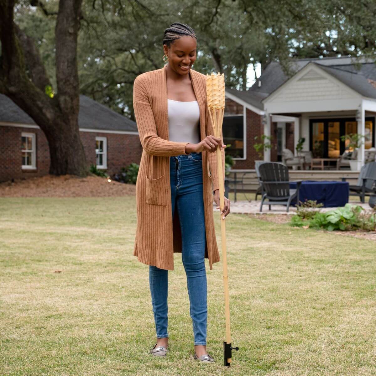 Beige long cardigan worn over white tank top and blue jeans.