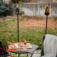 Tall black outdoor torches with flames, set on grassy yard with picnic table and blanket.