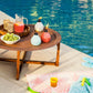 Colorful ceramic oil lamps on a wooden table by a pool.