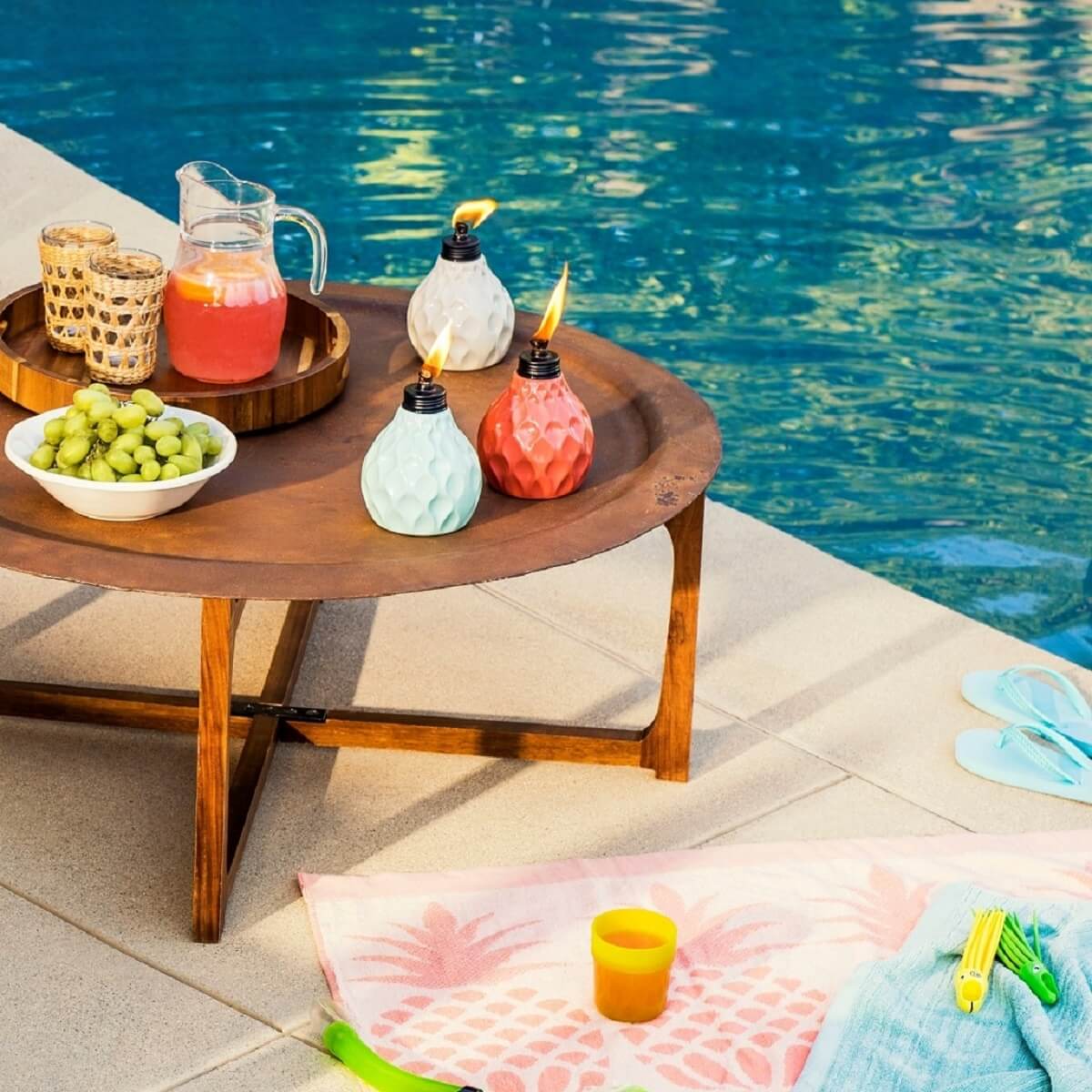 Colorful ceramic oil lamps on a wooden table by a pool.