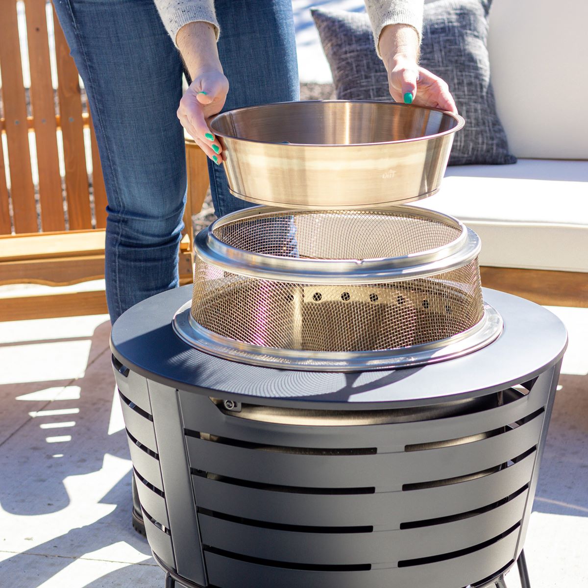 Silver outdoor fire pit with mesh grate and removable bowl.